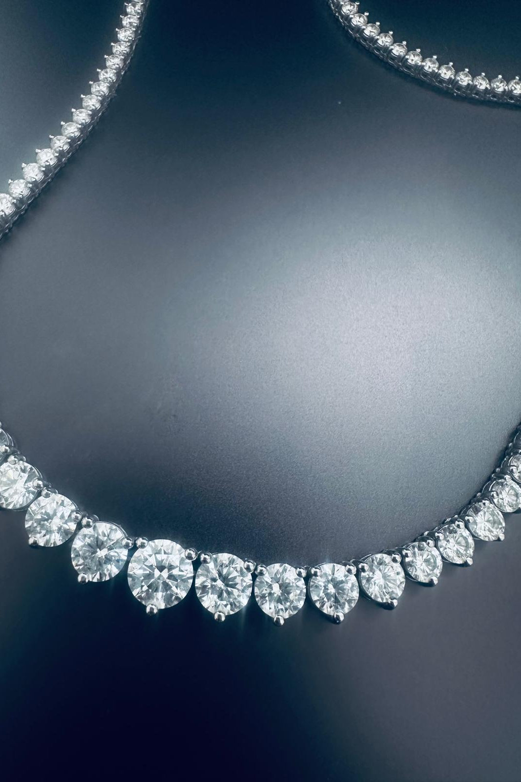 A close-up of a diamond necklace with a curved row of round-cut diamonds 
