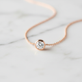Lab-grown diamond solitaire pendant necklace in rose gold on white marble